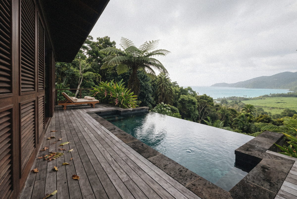 Piscine de la Villa Rivière en pierre volcanique, au-dessus de la rivière et de la forêt.